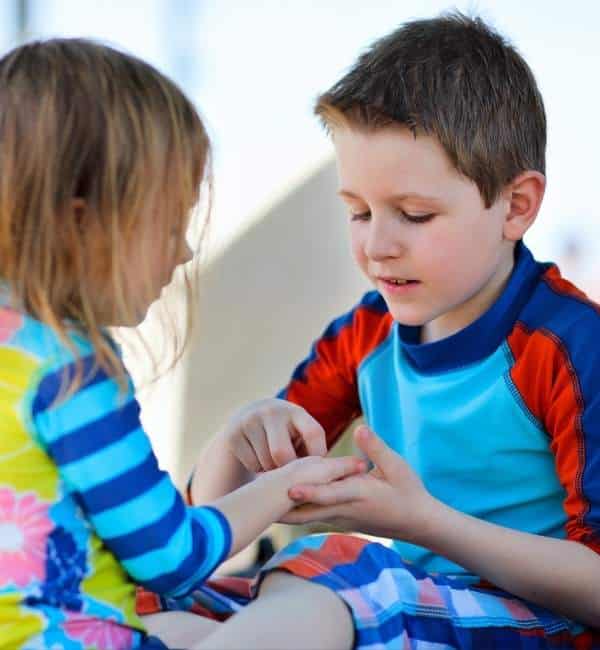 Child in blue/red shirt touches other child's palm as if communicating with gestures - speech therapy in san diego