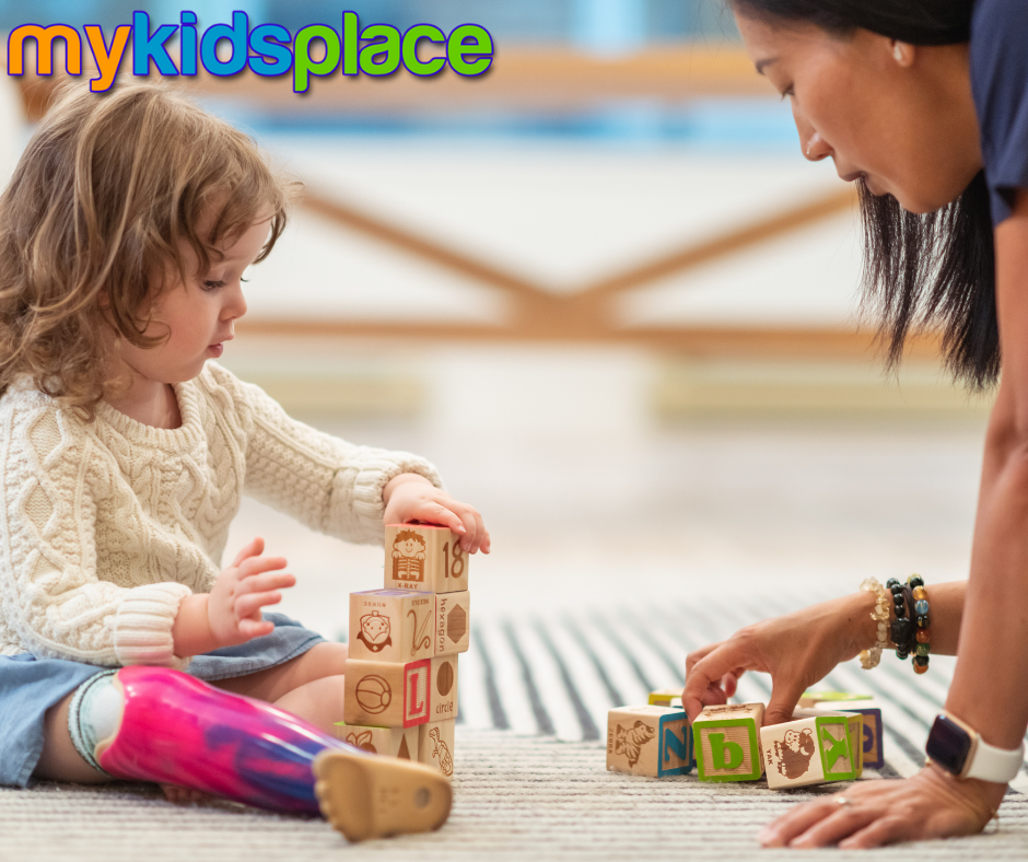 A young child with a purple/pink prosthetic leg practices stacking blocks with an occupational therapist to improve their fine motor skills.