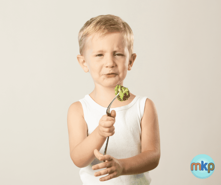 Grimacing child holds a piece of broccoli on a fork