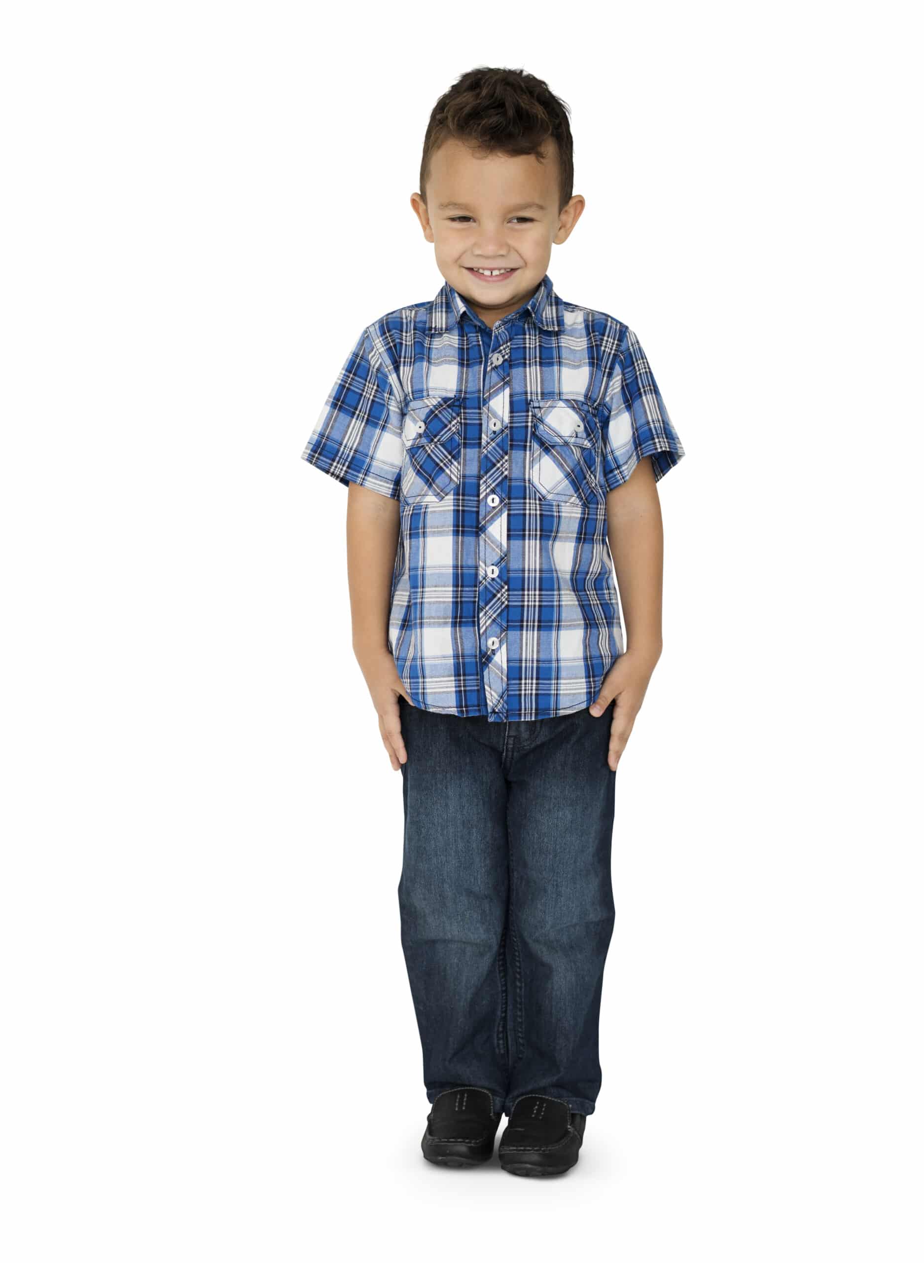 A smiling child in a plaid shirt and jeans holds their arms by their sides and stands with feet together.